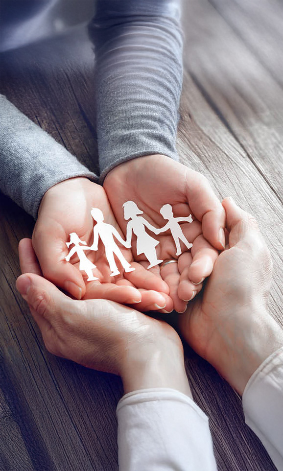 Hands holding paper cut-outs of a family symbolizing social responsibility.