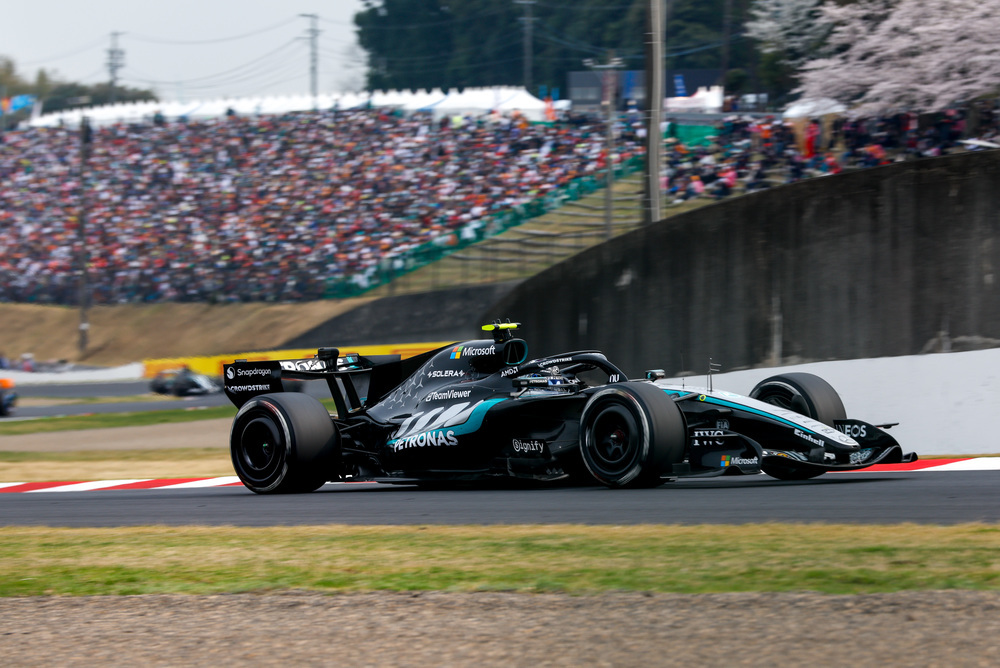 Mercedes F1 car driving past grandstands full of fans