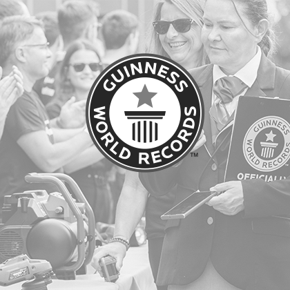 Imagen en blanco y negro: el logotipo de Guinness World Records sobre una foto de un evento mostrando las herramientas Einhell.
